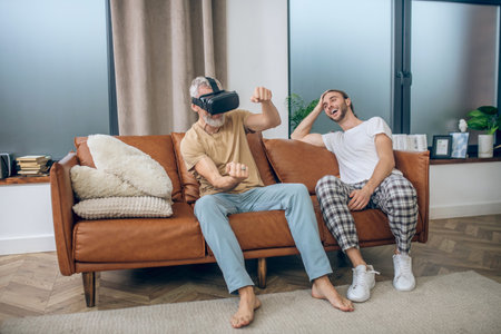 In VR glasses. Mature man in vr glasses driving a car, his partner sitting next to him