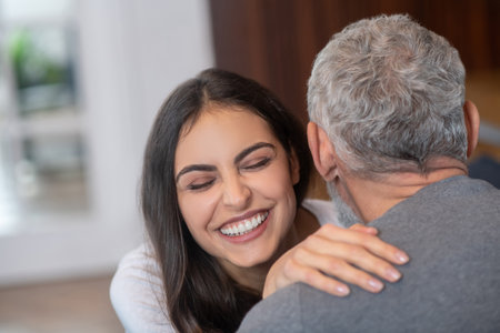 Happy relationships. A young long-haired woman hugging her grey-haired spouseの写真素材