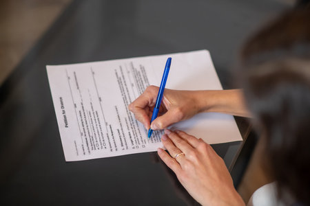 Divorcing process. A woman signing a petition for divorce with a pen