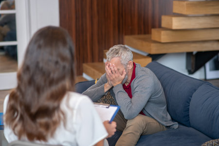 Therapy session. An upset man talking to his therapist during the sessionの写真素材