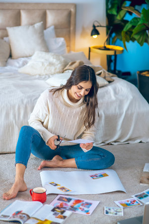 Wishlist. Cute young woman cutting pistures from magazines and making a wishlistの写真素材
