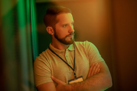 Observation. Pensive attractive young bearded man calmly looking to the side indoors with green...