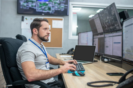 Mindfulness. Serious young bearded man sitting at workplace looking at computer screens his hands over keyboardの写真素材
