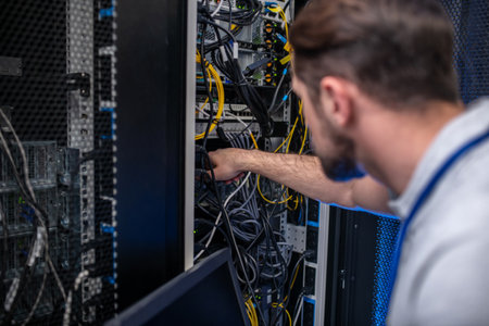 Work specifics. Back of head of involved man near open server rack, fingering wire, looking for problem spotの写真素材