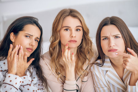 Afraid of aging. Three girls touching their skin looking unsatisfiedの写真素材