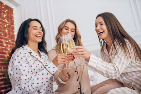 Champagne. Three young girls having pajama party and drinking champagneの写真素材