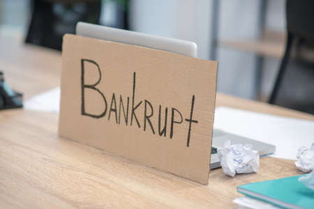Insolvency poster. Written insolvency poster standing near open laptop at work desk in office