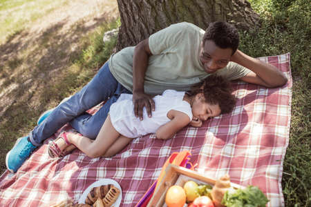 Resting. African american man and his cute kid having rest in the parkの写真素材