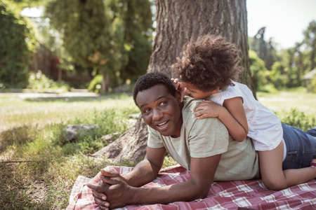 In the park. Dark-skinned man making selfie with his little daughter in the parkの写真素材