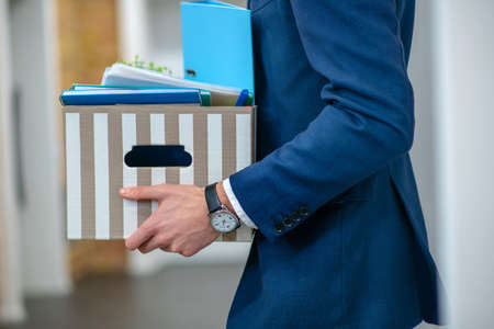 Personal belongings, office. Male hands with wristwatch holding striped box of personal belongings in office corridorの写真素材