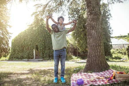 In the park. African american man spending time in the park with his daughter and looking happyの写真素材