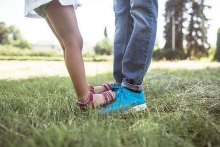 Togetherness. Close up picture of kids feet standing on dads feetの写真素材