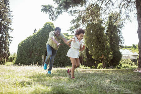Summertime. Dad and a cute girl running in the park and feeling happy