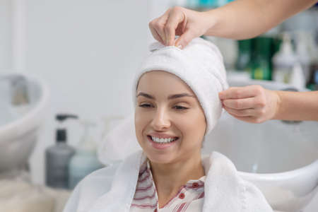 In a hair salon. Hairdresser covering her customers hair with a towelの写真素材