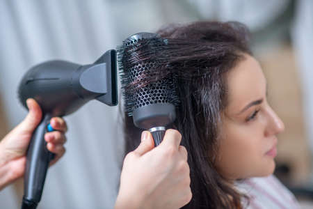 Hair styling. Dark-haired woman making hairstyling in a hair salonの写真素材
