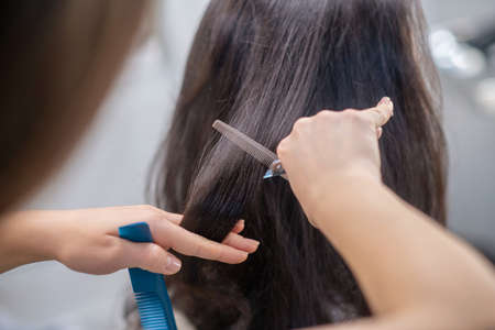 New style. Close up picrture of hand of hairdresser during the haircutting processの写真素材