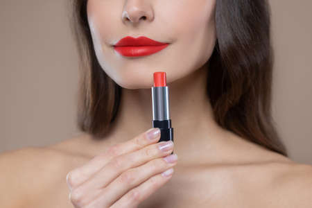 Red is trending. Lower part of womans face and bright red lipstick on beautiful lips and in handの写真素材