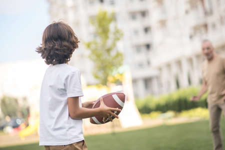 Playing ball. Dark-haired boy playing a ball with his dadの写真素材