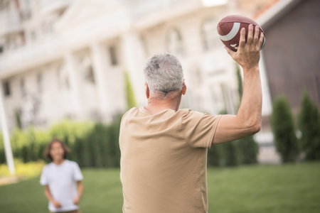 Good play. Dad throwing a ball while playing with his sonの写真素材