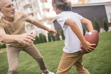 Excited. Dark-haired boy and his dad looking excited while playing ballの写真素材