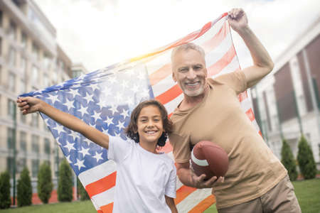 Americans. Dark-haired boy in a white tshirt and his dad with a flagの写真素材