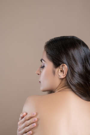 Gentle touch. Dark-haired pretty woman with her back holding shoulder with hand and turning face to...