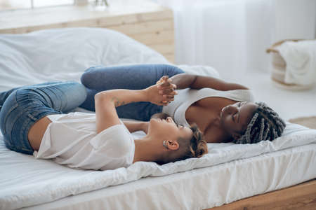 Love. Two girls lying on the bed and holding hands