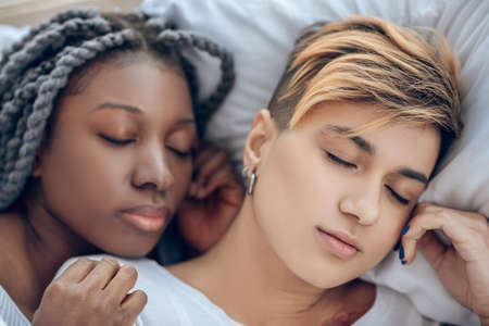 Having a nap. Two young girls lying on the bed and nappingの写真素材