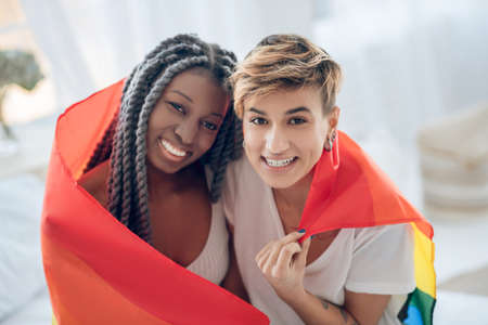 Happy people. Two young girls with a rainbow flag smiling positively