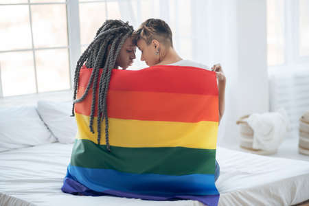 Closeness. Two young girls with a rainbow looking in loveの写真素材