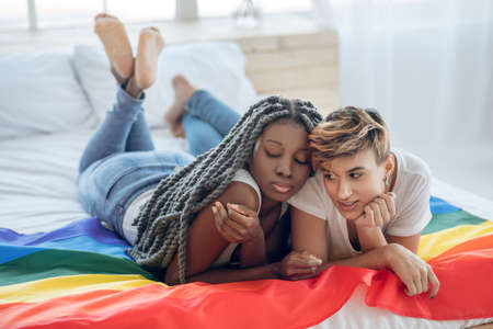 Relaxed. Two young girls with a rainbow flag lying on the floorの写真素材
