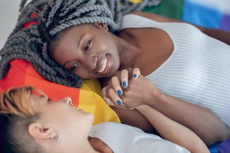 Happiness. Two young girls with a rainbow flag smiling to each otherの写真素材