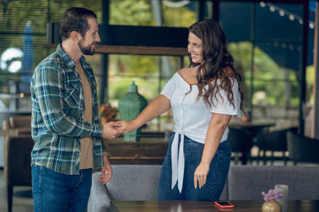 Acquaintance. Smiling young adult man and woman standing opposite each other with outstretched hand getting acquaintedの写真素材