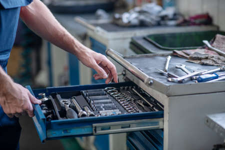 Work tool. Male hands opening drawer with large selection of working tools in car workshop