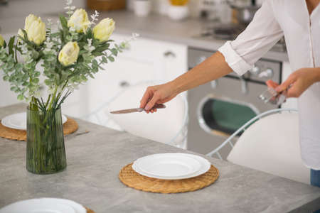 Serving the table. Woman in white shirt serving the table for dinner