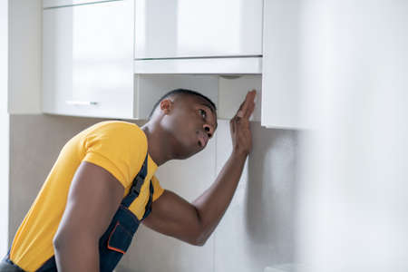 Busy. Dark-skinned service man working in the kitchen and looking concentrated on workの写真素材