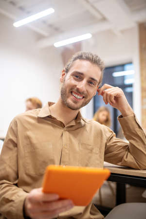 In the office. Handsome young bearded guy sitting in the office and looking positiveの写真素材