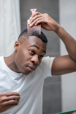 African american guy in white tshirt doing his hair