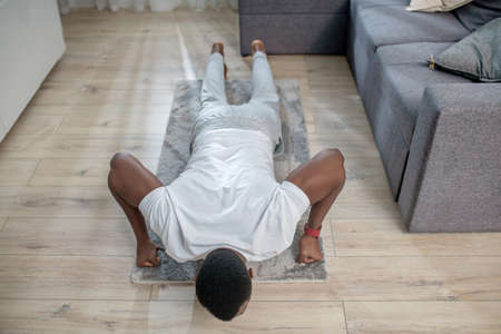 African american guy in white clothes doing morning exercisesの写真素材