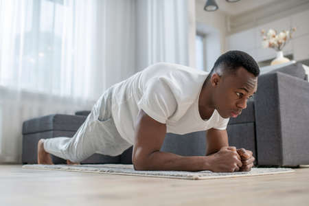 African american guy in white clothes doing morning exercisesの写真素材