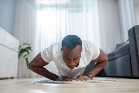 African american guy in white clothes having ahome workout