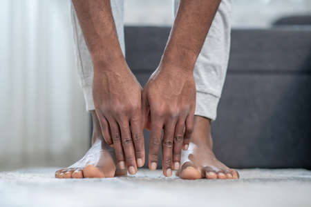 Close up picture of dark-skinned mans hands touching the floorの写真素材