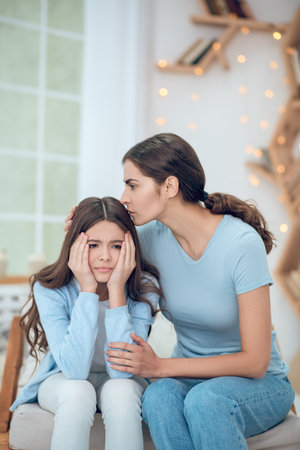 Upset daughter and caring mom sitting at homeの写真素材