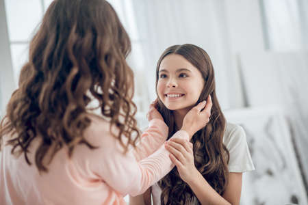 Mom touching her happy looking daughters hairの写真素材