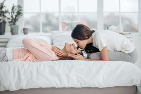 Daughter touching head of lying young motherの写真素材