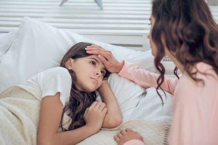 Mom touched head of sad looking daughterの写真素材