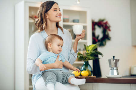 Shining beautiful woman with child drinking coffeeの写真素材