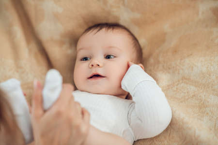Moms hands holding legs of lying babyの写真素材