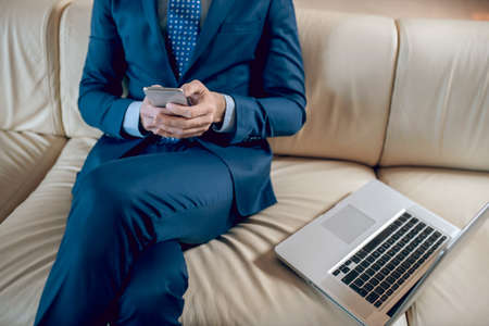 Man in a suit sitting in the office on the sofaの写真素材