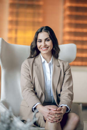 Pretty businesswoman sitting in the armchair and smiling